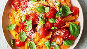 Cremige Kürbis-Pasta mit gerösteten Kirschtomaten, frischem Basilikum und geriebenem Parmesan in einer hellen, runden Schale. - Foto: Simone Neufing/MOE‘S QUICK & EASY FOOD Cremige Kürbis-Pasta mit gerösteten Kirschtomaten, frischem Basilikum und geriebenem Parmesan in einer hellen, runden Schale. - Foto: Simone Neufing/MOE‘S QUICK & EASY FOOD
