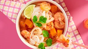 Laksa-Nudelsuppe in weißen Schalen mit Reisnudeln, Garnelen, Butternusskürbiswürfeln, frischem Koriander und Limetten, serviert auf buntem Untergrund mit Essstäbchen. - Foto: LECKER @ Bauer Media Group Laksa-Nudelsuppe in weißen Schalen mit Reisnudeln, Garnelen, Butternusskürbiswürfeln, frischem Koriander und Limetten, serviert auf buntem Untergrund mit Essstäbchen. - Foto: LECKER @ Bauer Media Group