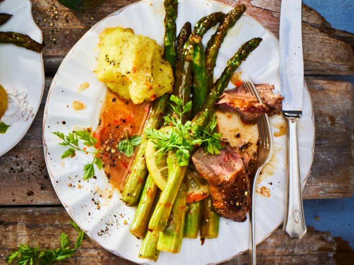 Lammfilet auf grünem Spargel mit Kartoffel-Parmesan Bällchen auf einem Teller angerichtet