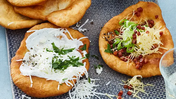 Goldbraune Langos mit Sauerrahm, Käse, Schinkenwürfel und Lauchzwiebeln. - Foto: LECKER @ Bauer Media Group Goldbraune Langos mit Sauerrahm, Käse, Schinkenwürfel und Lauchzwiebeln. - Foto: LECKER @ Bauer Media Group