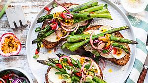 Drei Stullen mit gratiniertem Ziegenkäse und gebratenem grünen Spargel auf einem weißen Teller - Foto: House of Food / Bauer Food Experts KG