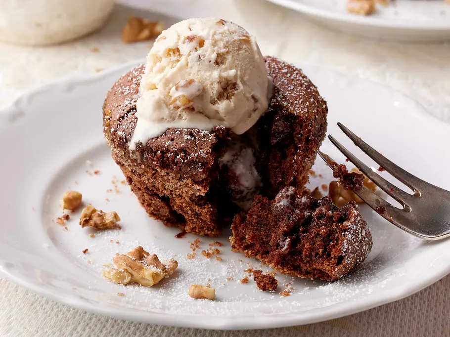 Lava Cake steht angeschnitten auf einem kleinen Kuchenteller. Eine Kugel Walnusseis ist darauf serviert.