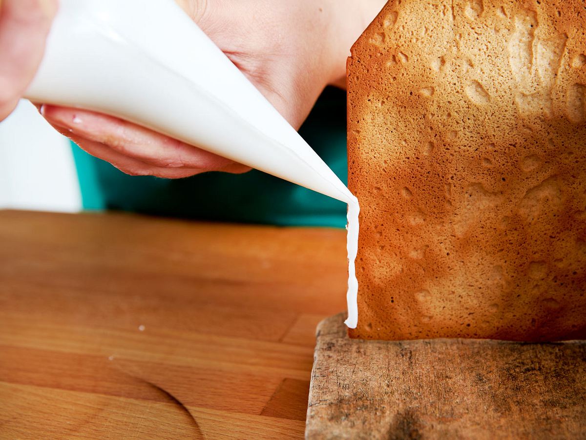 Lebkuchenhaus-Wände mit Zuckerguss kleben