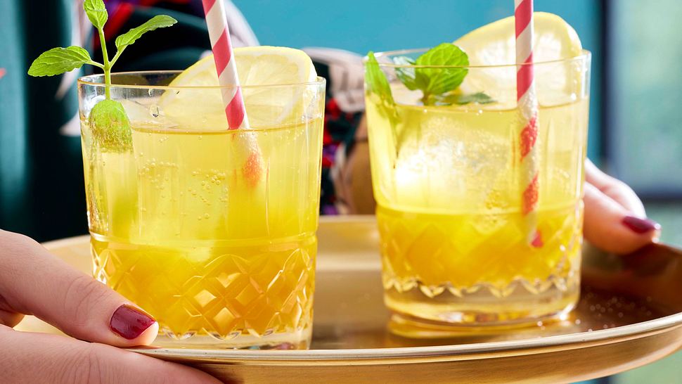 Limoncello-Maracuja-Spritz in zwei Gläsern mit Zitronenscheibe und Minze serviert, auf einem goldenen Tablett.  - Foto: House of Food / Bauer Food Experts KG