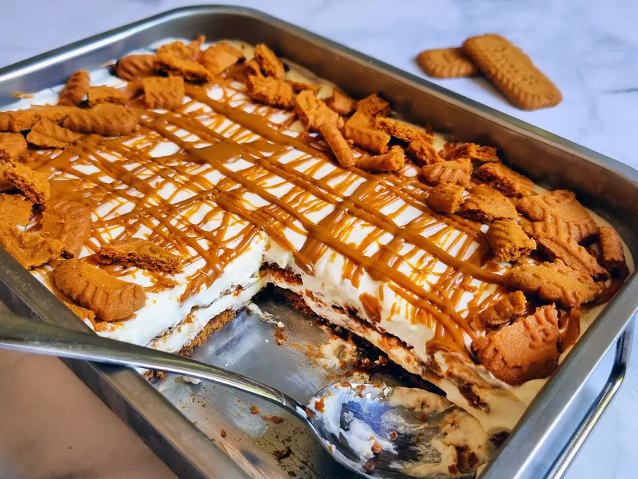 Lotus-Tiramisu Rezept Eine Auflaufform mit Lotus-Tiramisu, bedeckt von einer Karamell-Sauce und mit mehreren Lotus-Keksen garniert.