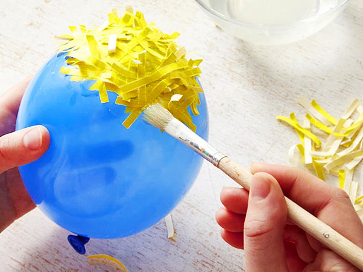 Luftballon mit Papierschnipseln bekleben