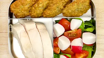 Geschnittenes Hähnchenbrustfilet, knusprige Müslibrötchen sowie ein frischer Salat aus Tomaten, Radieschen und Blättern, appetitlich sortiert in einer Edelstahl-Lunchbox. - Foto: LECKER @ Bauer Media Group