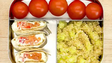 Drei Wrapstücke mit Frischkäse und Gemüse, dazu Kirschtomaten und Quinoa-Salat mit Gurke appetitlich in einer Edelstahl-Lunchbox angerichtet. - Foto: LECKER @ Bauer Media Group