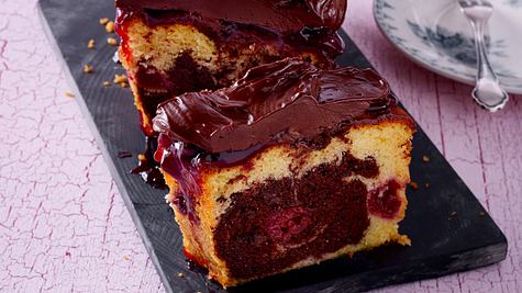 Angeschnittener Mamor-Kirsch-Kuchen aus der Kastenform mit dicker Schoko-Ganache mit Kuchenteller im Hintergrund - Foto: House of Food / Bauer Food Experts KG