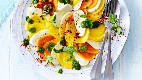 Mango-Papaya-Caprese mit Pestoklecksen und Zitronenmelisse, angerichtet auf einem weißen Teller. - Foto: House of Food / Bauer Food Experts KG