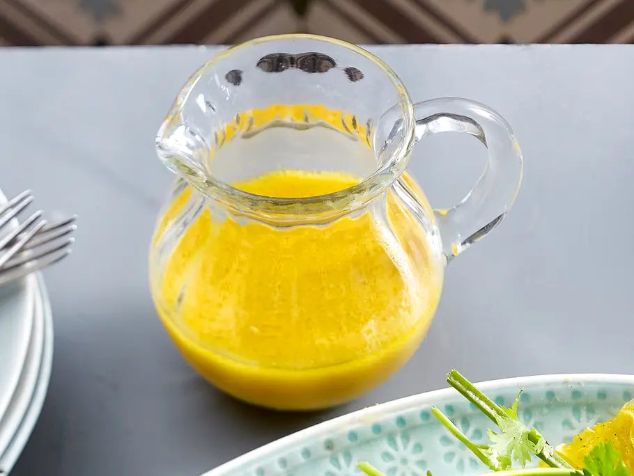 Eine kleine Glaskaraffe mit gelben Mangodressing