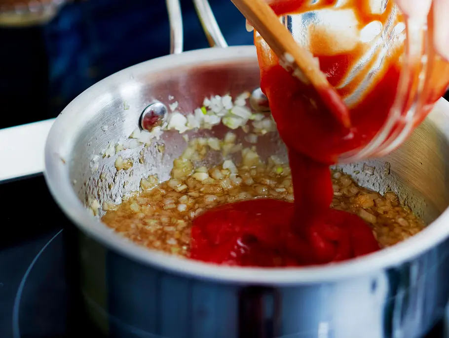 Marinade für Spareribs zubereiten Ketchup wird zu den karamellisierten Zwiebeln gegeben.
