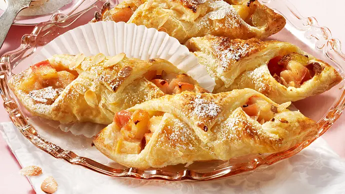 Marzipan-Apfeltaschen mit Puderzucker bestäubt auf einem alten rosa Glasteller - Foto: LECKER @ Bauer Media Group Marzipan-Apfeltaschen mit Puderzucker bestäubt auf einem alten rosa Glasteller - Foto: LECKER @ Bauer Media Group