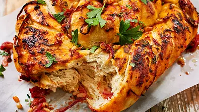 Mediterranes Grillbrot mit Kräutern, Tomaten und Petersilie auf Backpapier serviert, frisch angerissen. - Foto: LECKER @ Bauer Media Group Mediterranes Grillbrot mit Kräutern, Tomaten und Petersilie auf Backpapier serviert, frisch angerissen. - Foto: LECKER @ Bauer Media Group