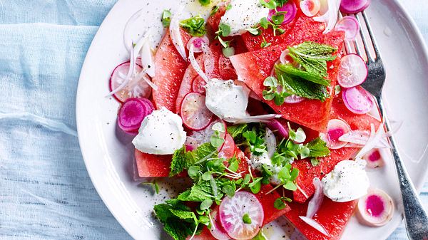 Melonen-Radieschen-Salat mit Ziegenfrischkäse und frischer Minze mit einer Gabel auf einem weißen Teller - Foto: Foto: House of Food / Bauer Food Experts KG
