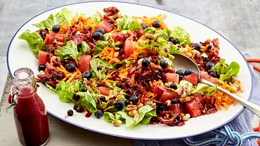 Bunte Blattsalate, Möhren, Wassermelone, Blaubeeren, Erdnüsse und knuspriger Speck liegen angerichtet auf einer weißen Platte. - Foto: LECKER @ Bauer Media Group Bunte Blattsalate, Möhren, Wassermelone, Blaubeeren, Erdnüsse und knuspriger Speck liegen angerichtet auf einer weißen Platte. - Foto: LECKER @ Bauer Media Group