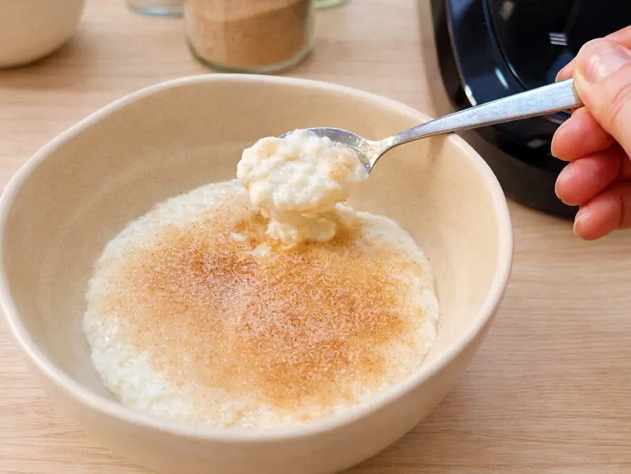 Eine Schüssel Milchreis mit Zimtzucker stehe vor dem Monsieur Cuisine Compact, im Hintergrund ein Glas mit Zimtzucker