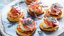 Sechs Blini-Häppchen mit Stremellachs stehen auf einem runden Serviertablett - Foto: LECKER @ Bauer Media Group Sechs Blini-Häppchen mit Stremellachs stehen auf einem runden Serviertablett - Foto: LECKER @ Bauer Media Group
