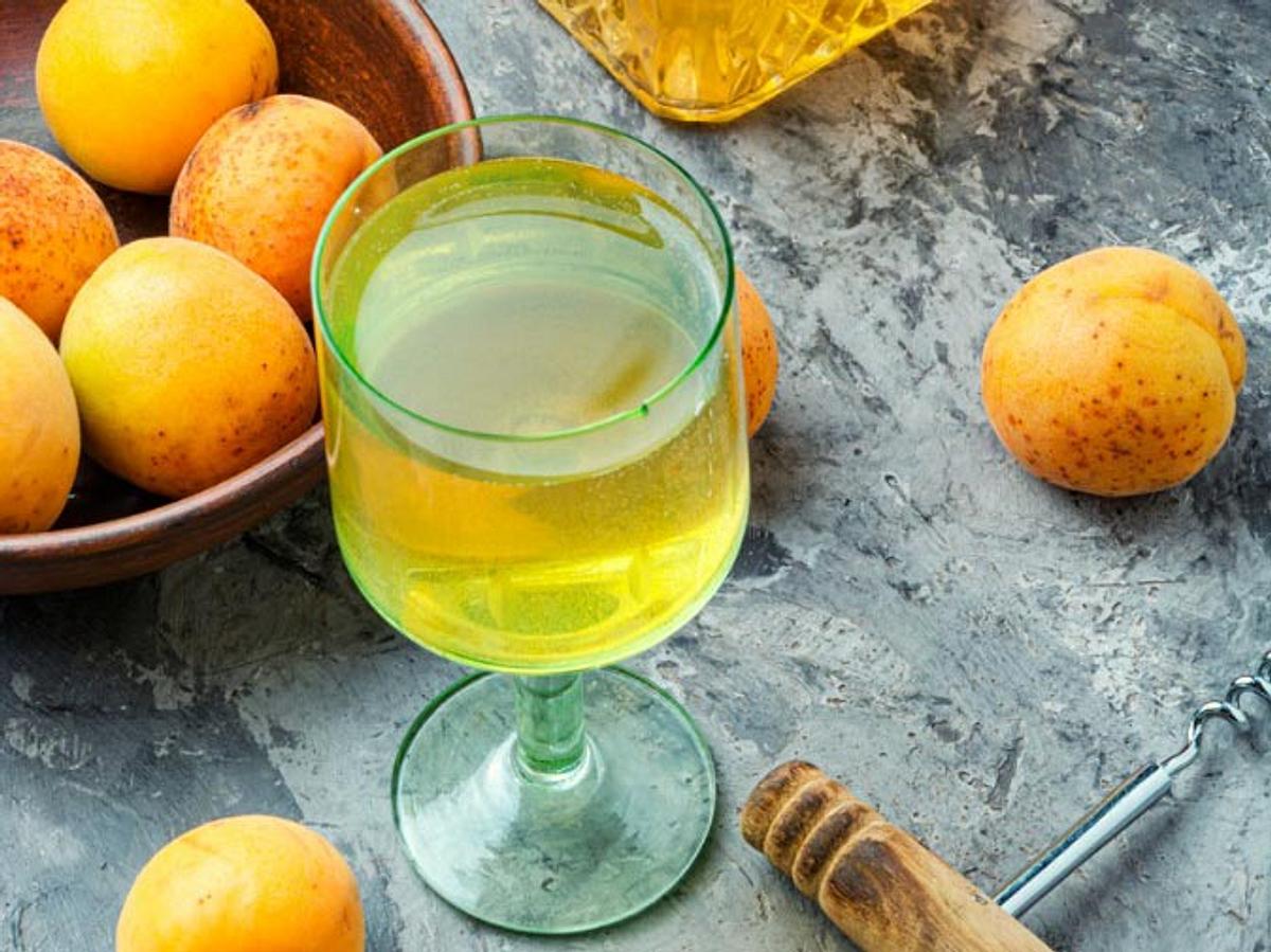 Mirabellenlikör befindet sich in einem Likörglas. Frische Mirabellen liegen darum herum. Rezept