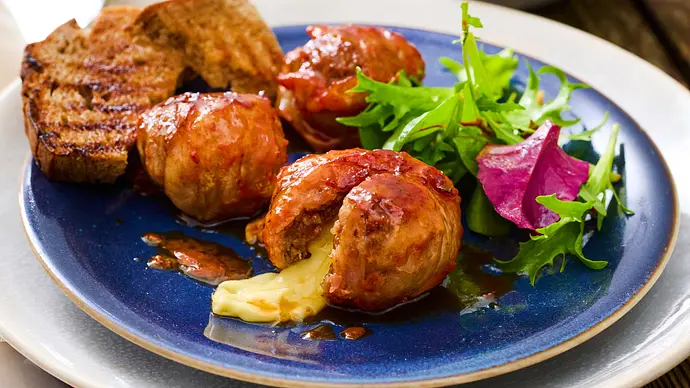 Drei gegrillte Moink Balls auf einem Teller, aus einem läuft geschmolzener Käse - Foto: LECKER @ Bauer Media Group