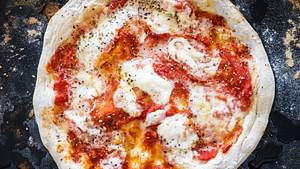 Neapolitanische Pizza mit Tomatensauce und Mozzarella auf bemehlter schwarzer Schieferplatte. - Foto: House of Food / Bauer Food Experts KG
