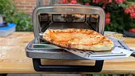 Eine goldbraun gebackene Pizza Margherita wird mit einem Schieber aus dem Ninja Artisan Outdoor-Elektro-Pizzaofen geholt. - Foto: Emily Beckmann / LECKER.de Eine goldbraun gebackene Pizza Margherita wird mit einem Schieber aus dem Ninja Artisan Outdoor-Elektro-Pizzaofen geholt. - Foto: Emily Beckmann / LECKER.de