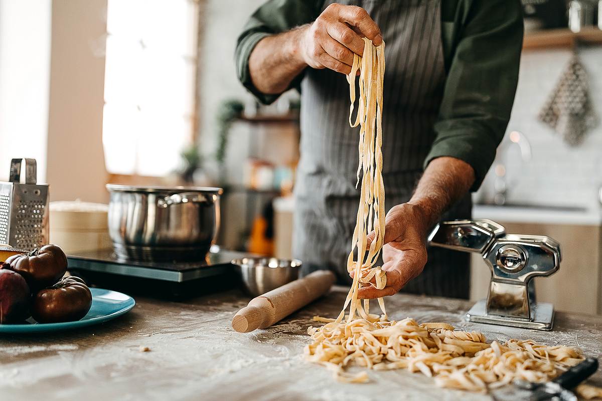 Beste Nudelmaschine: Mann stellt frische Pasta mit einem manuellen Pastamaker her
