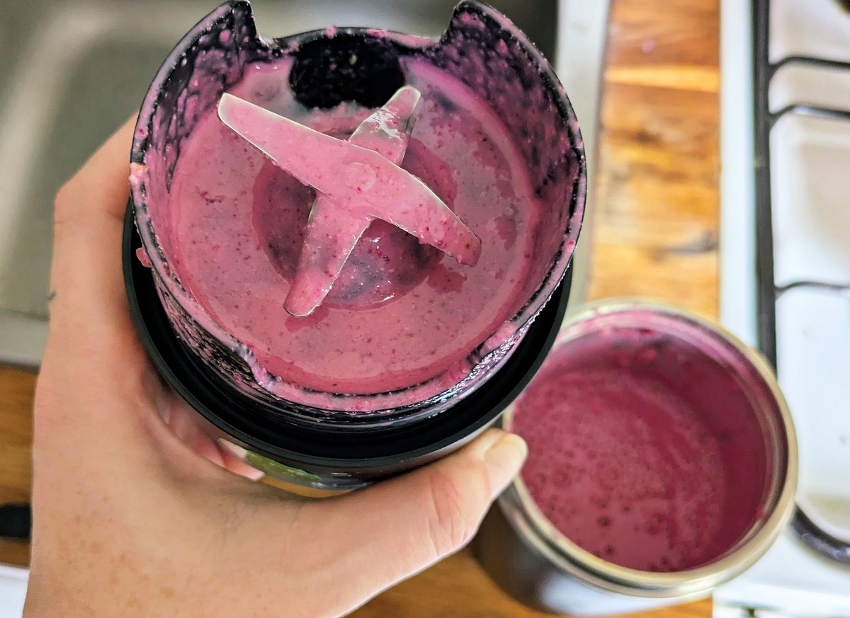 nutribullet Flip Smoothie-Maker Klingen Der Mixaufsatz des nutribullet Flip wird abgenommen, die Klingen sind mit pinkem Beerensmoothie bedeckt, der Smoothiebecher steht darunter.