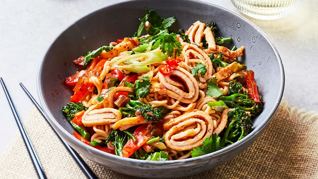 Gerollte Omelettstreifen auf Gemüse-Bratnudeln in einer grauen Bowl, daneben Essstäbchen - Foto: LECKER @ Bauer Media Group