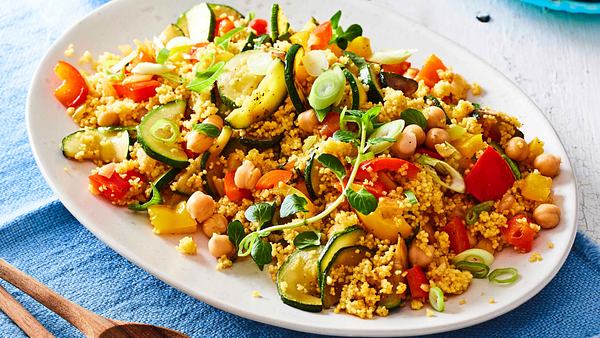 Couscous zu Joghurt-Minz-Dip auf einem weißen Servierteller mit frischem Oregano, daneben liegt Servierbesteck aus Holz - Foto: House of Food / Bauer Food Experts KG