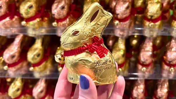 Eine Hand hält einen kleinen Eine Hand hält einen kleinen Lind-Schokohasen und im Hintergrund sind die vollen Supermarktregale von glitzernden großen Lindt-Osterhasen zu sehen und im Hintergrund sind die vollen Supermarktregale von glitzernden großen Lindt-Osterhasen zu sehen - Foto: LECKER @ Bauer Media Group / Nicole Molitor