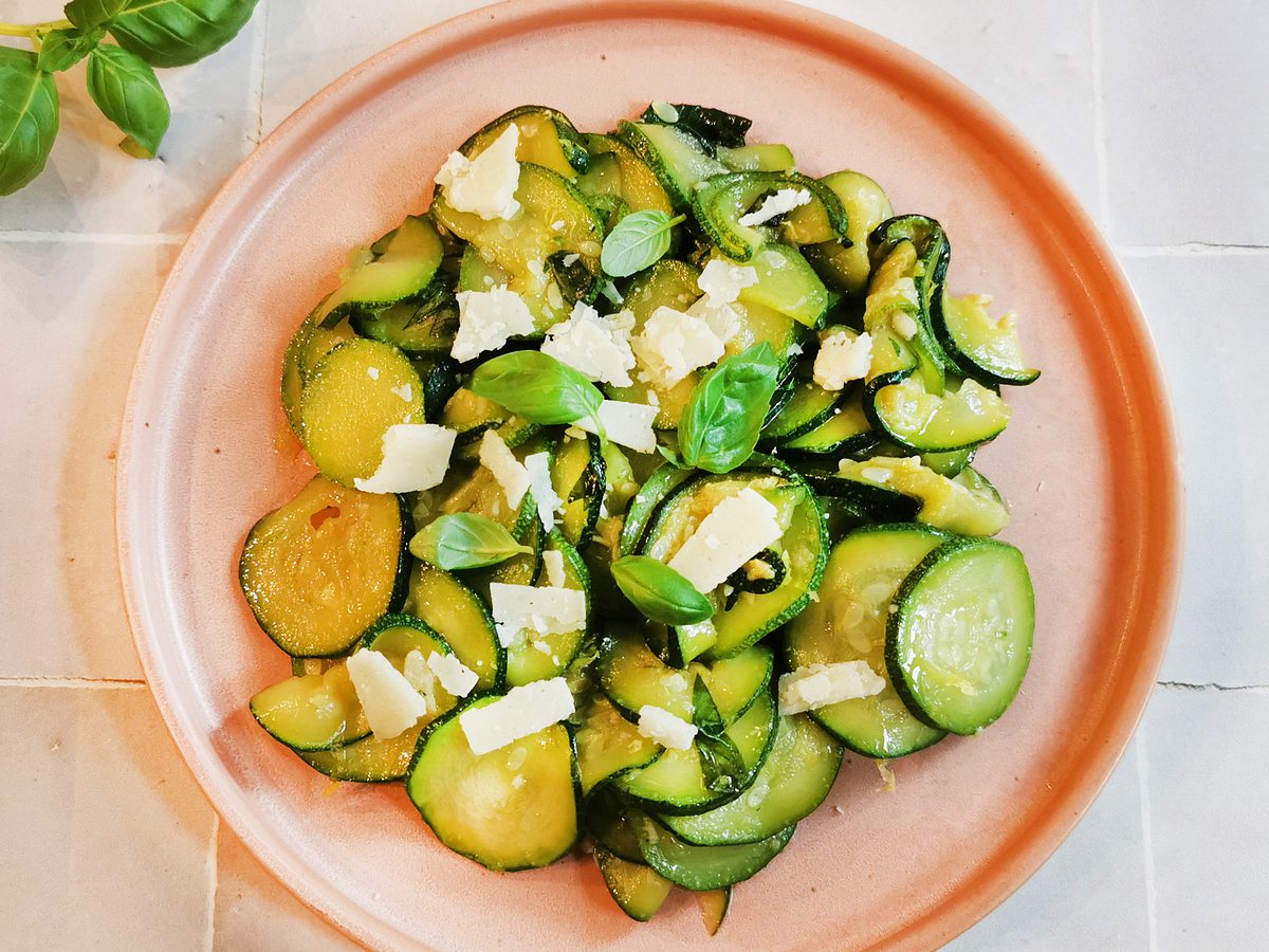 Mild gewürzte Zucchini mit Parmesan auf einem Teller angerichtet.