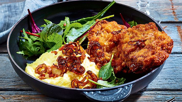 Panierte Rindersteaks mit Kartoffelstampf, Röstzwiebel und grünem Salat in einer gusseisernen Pfanne - Foto: House of Food / Bauer Food Experts KG