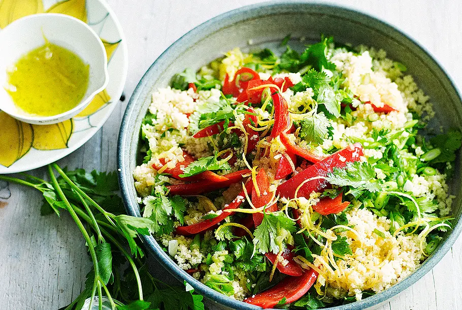 Eine Schüssel mit Couscous, Paprika, Kräutern und Dressing.