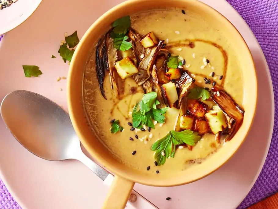 Paprika-Spargelsuppe mit Halloumi in einer gelben Schüssel mit einem Löffel angerichtet.