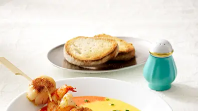 Das Bild zeigt einen Teller Paprikacremesuppe mit Jakobsmuscheln am Spieß - Foto: LECKER