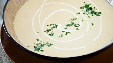 Cremige helle Suppe aus Pastinaken in einer dunklen Suppenschüssel. - Foto: LECKER @ Bauer Media Group