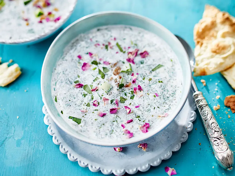 Persische Joghurtsuppe Abdoogh Khiar Rezept Die persische Joghurtsuppe mit vielen Kräutern und Gurken in einer Schüssel serviert.