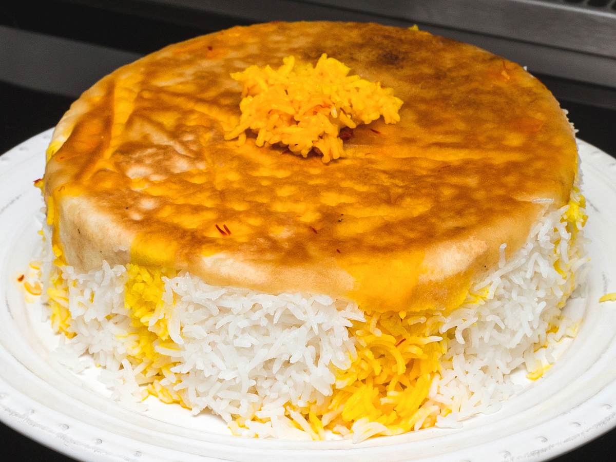 Persischer Reis mit einer Kruste aus Brot liegt wie ein Kuchen auf einem Teller
