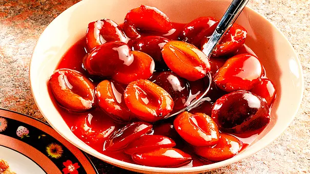 Auf einem tiefen Teller befindet sich das Pflaumenkompott. Die halbierten Früchte sind gut zu erkennen. - Foto: LECKER @ Bauer Media Group