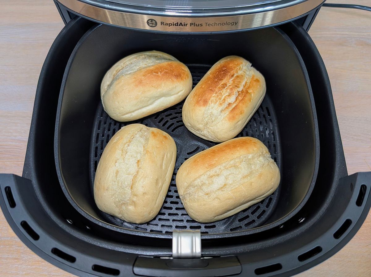 Blick von oben auf ungleichmäßig gebräunte Aufbackbrötchen, die im Garkorb des Philips Airfryer 3000 Series 6,2 l liegen.