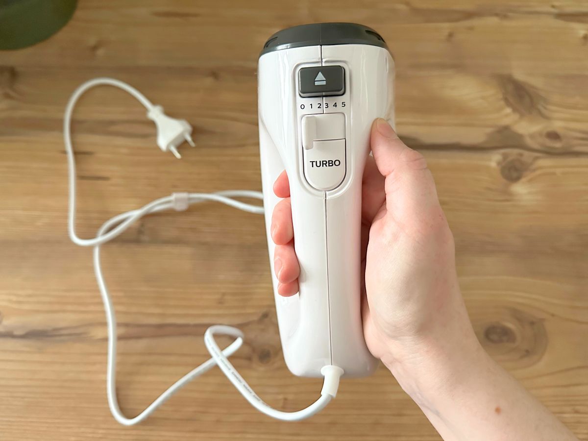 Topshot von einer Hand, die den Philips-Handmixer so hält, dass seine intuitive Bedienung mit Schiebeschalter sichtbar wird