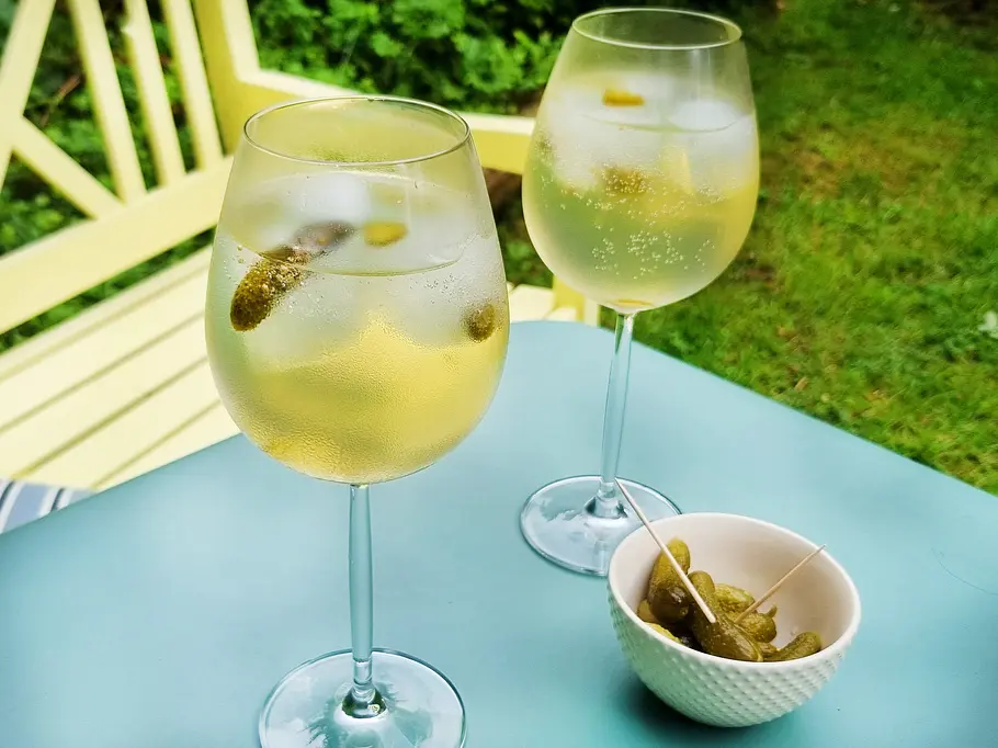 Pickled Sauvignon Blanc in zwei Stielgläsern mit Gewürzgurke serviert,