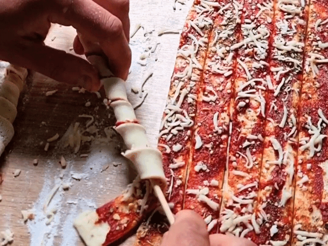 Pizzastreifen werden um Holzspieß gewickelt.