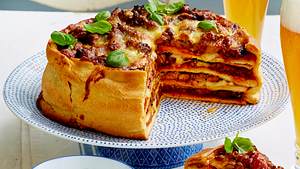 Angeschnittener Pizzakuchen XXL auf einem Servierteller mit Dip und frischem Basilikum - Foto: House of Food / Bauer Food Experts KG