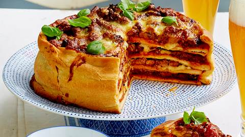 Angeschnittener Pizzakuchen XXL auf einem Servierteller mit Dip und frischem Basilikum - Foto: House of Food / Bauer Food Experts KG