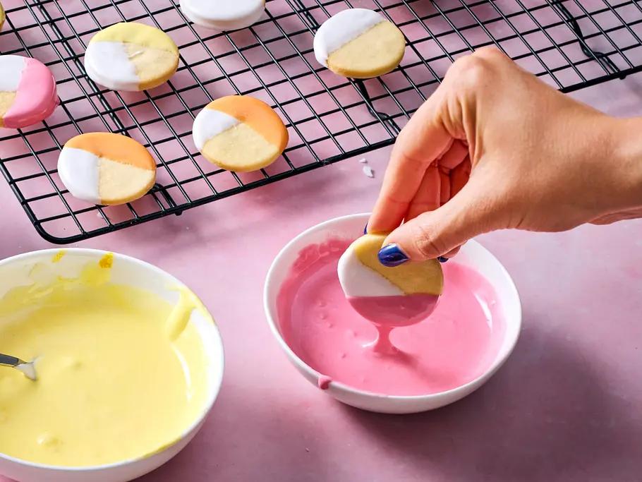 Plätzchen in Zuckerguss tunken Ein Cookie wird in pinken Zuckerguss getunkt.