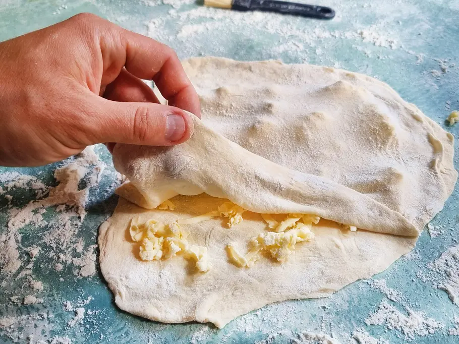 Plunderteig herstellen Zwei Teigschichten mit geraspelter Butter dazwischen sind zu erkennen.