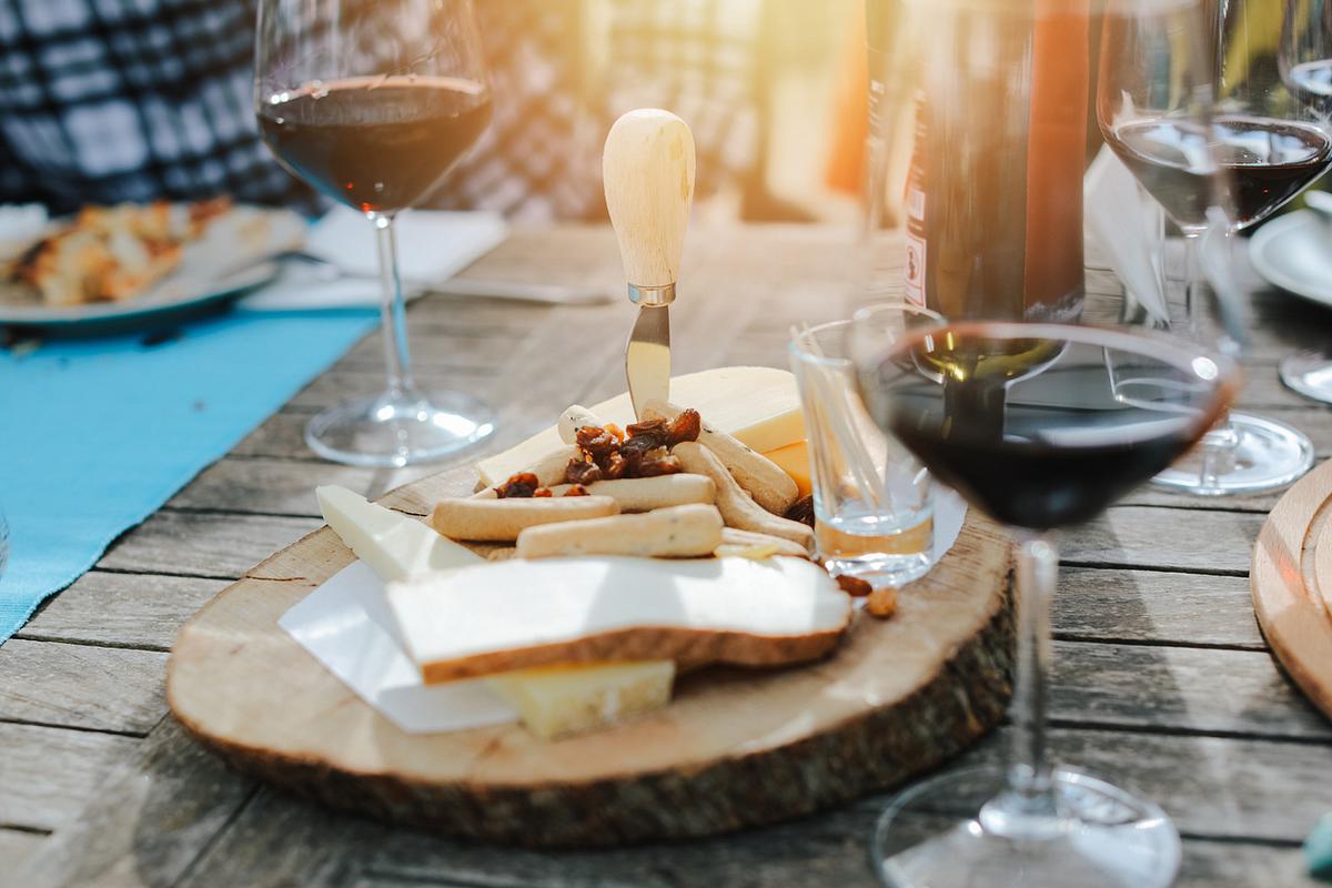 Zwei mit Rotwein gefüllte Weingläser neben einer Käseplatte