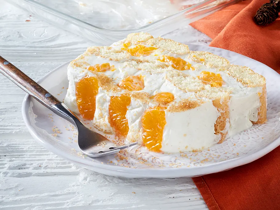 Quarkdessert mit Mandarinen: Ein Stück liegt auf einem Teller. Man erkennt die Schichten aus Biskuit, Creme und Mandarinen.